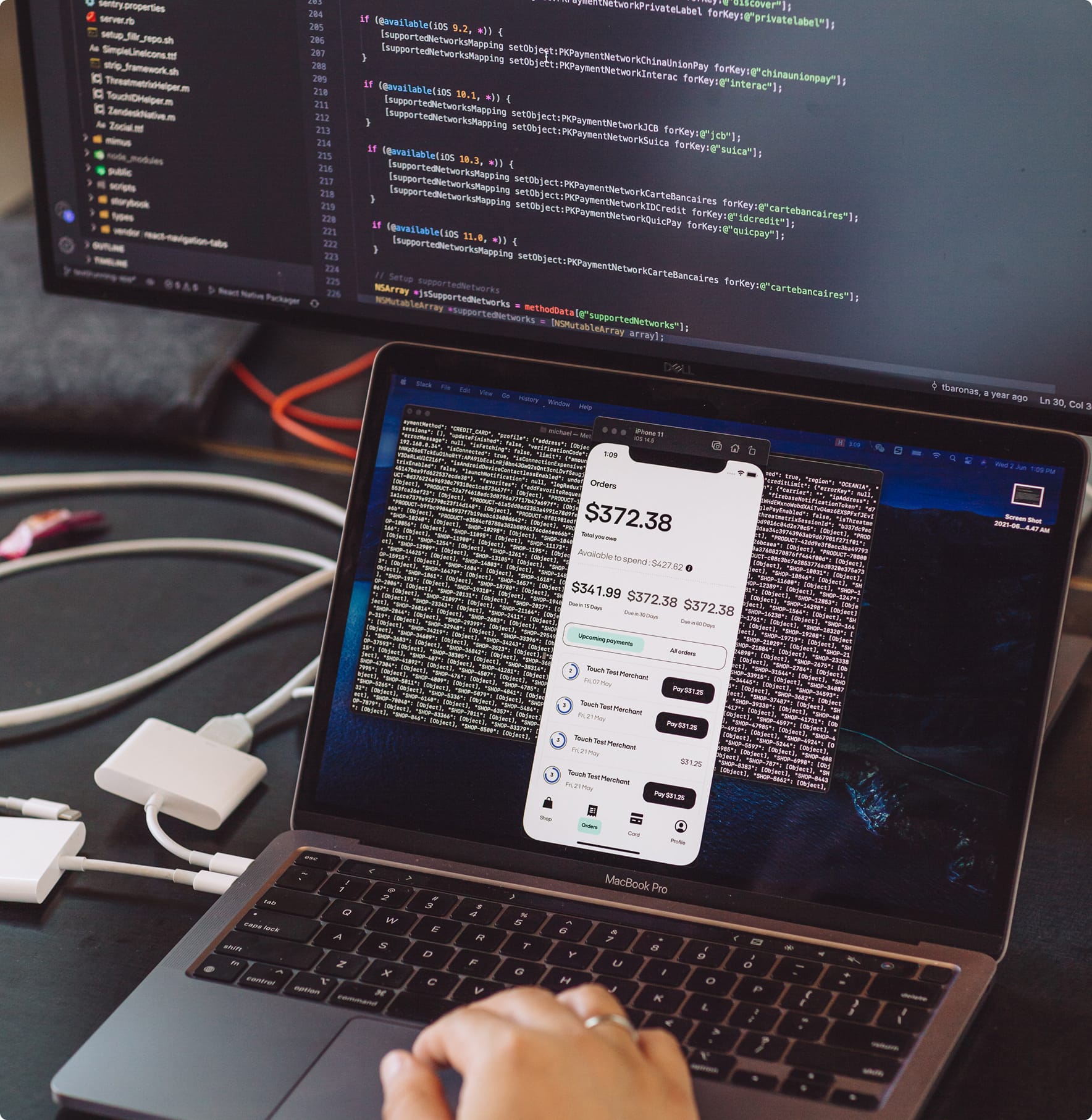 Laptop showing a mobile app design alongside code on a monitor